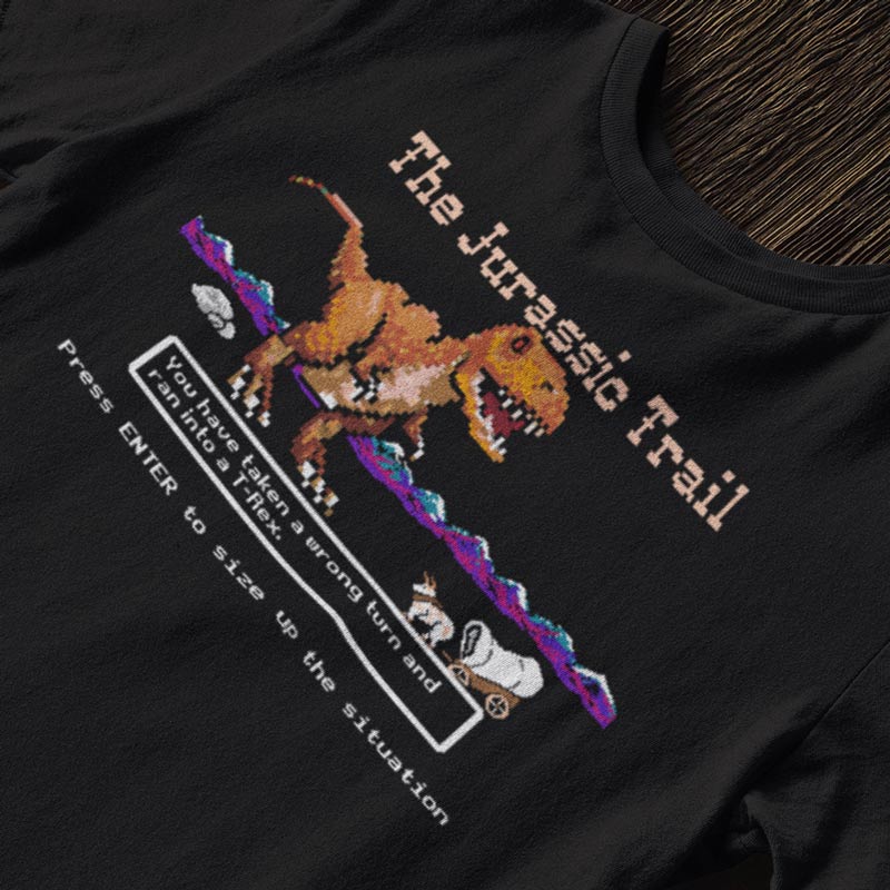 Close-up of Jurassic Trail shirt – funny 8-bit T-Rex attacking ox and wagon