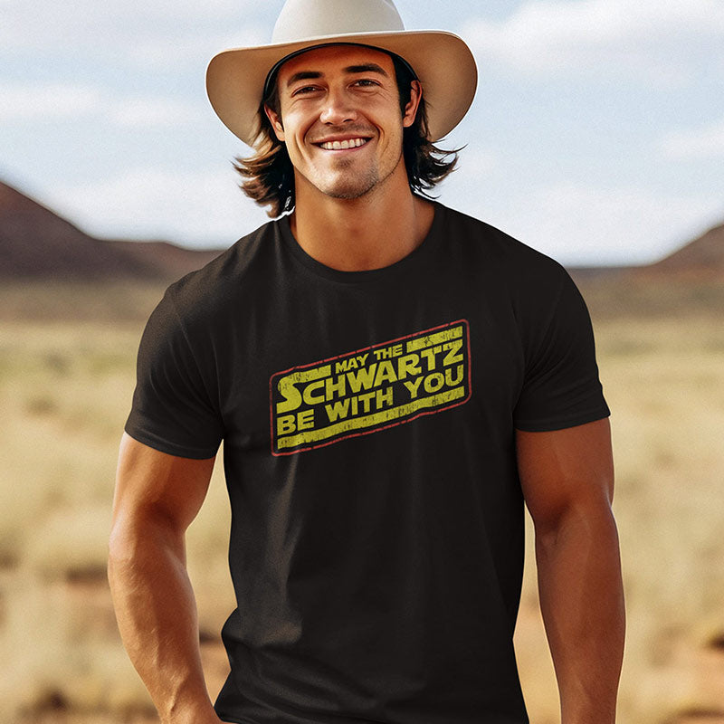 Guy wearing 80s movie t shirt from Dodo Tees. The retro t shirt reads May The Schwartz Be With You.