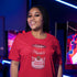 smiling woman wearing an 80s t shirt in red with a print of a cartoon Mario's cream of mushroom soup can in an arcade