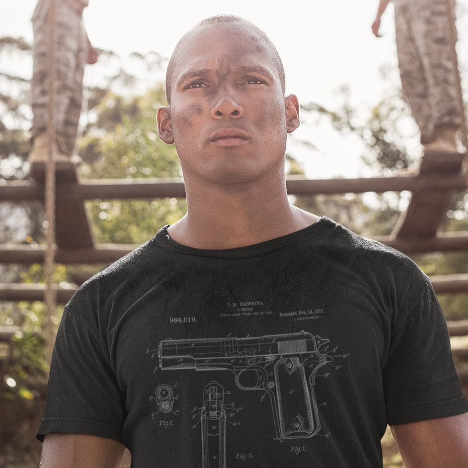 Guy wearing an army shirt featuring a 1911 pistol patent in grey. The gun tee shirts are side-seamed for a structure that accentuates your physique.