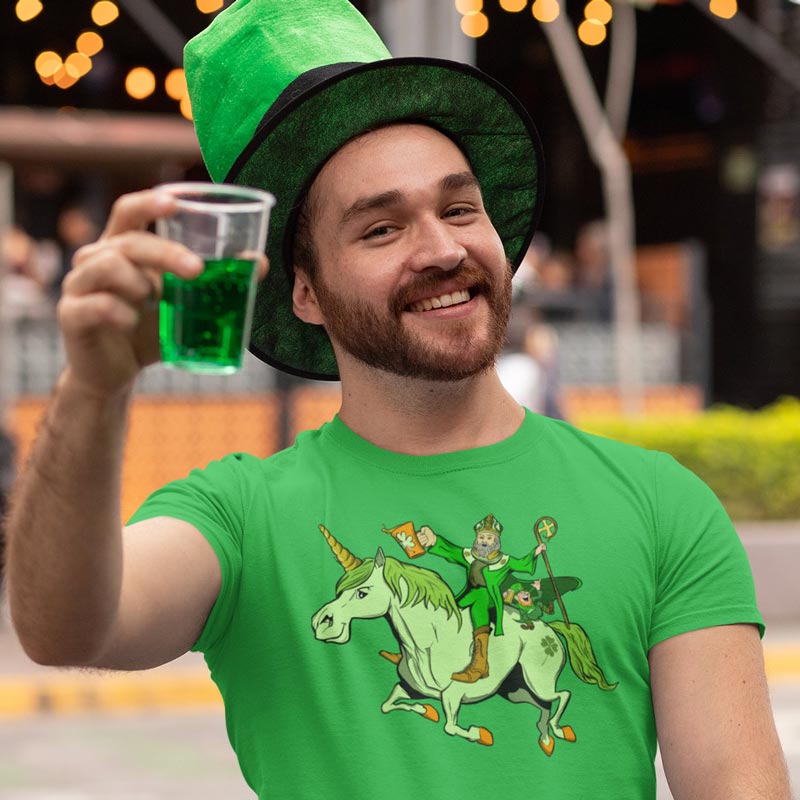 Man drinking green beer and wearing a Saint Pattys shirt with a unicorn, St. Patrick and a leprechaun.