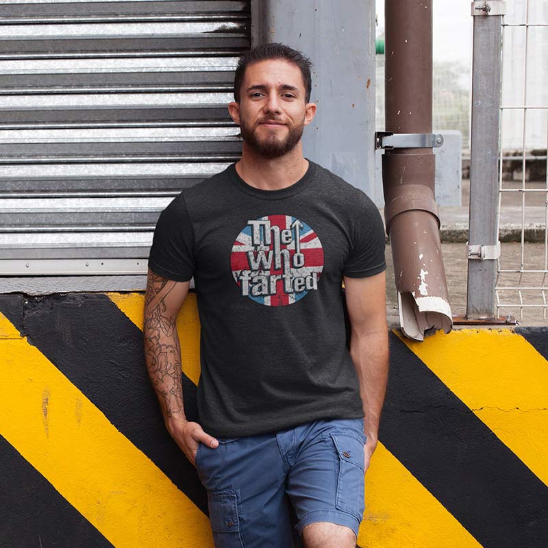 man leaning against wall wearing band parody shirt with the who farted funny logo