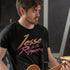 man wearing band t shirt with vintage orange and pink jesse and the rippers logo playing guitar in studio
