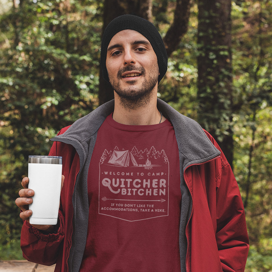 Man in woods wearing Dodo Tees camping gifts for men Camp Quichterbitchen camping shirt. The funny dad shirt has vintage looking typography and a distressed vibe.