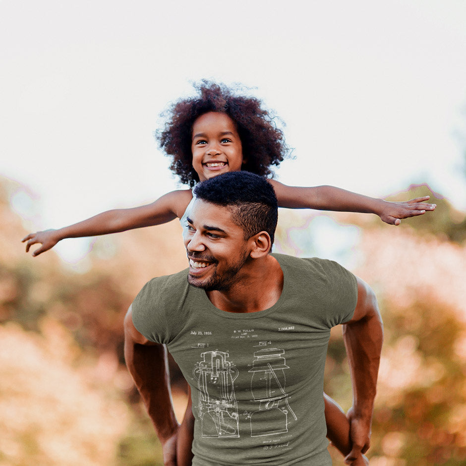 dad giving daughter a piggy back ride. Man is wearing the Dodo Tees camping shirt featuring a 1935 lantern patent. the manly shirts feature butter soft fabric.