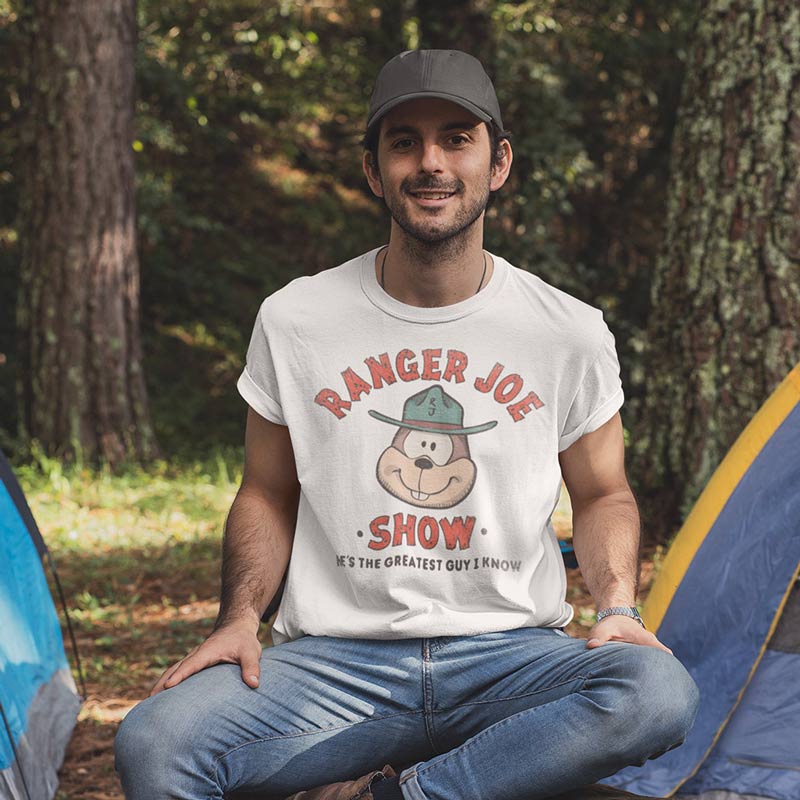 man sitting at camp site trying on his ranger joe camping shirt