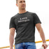 man wearing heather charcoal funny dad t shirt with the words love monger. The funny shirts are designed by Dodo Tees.