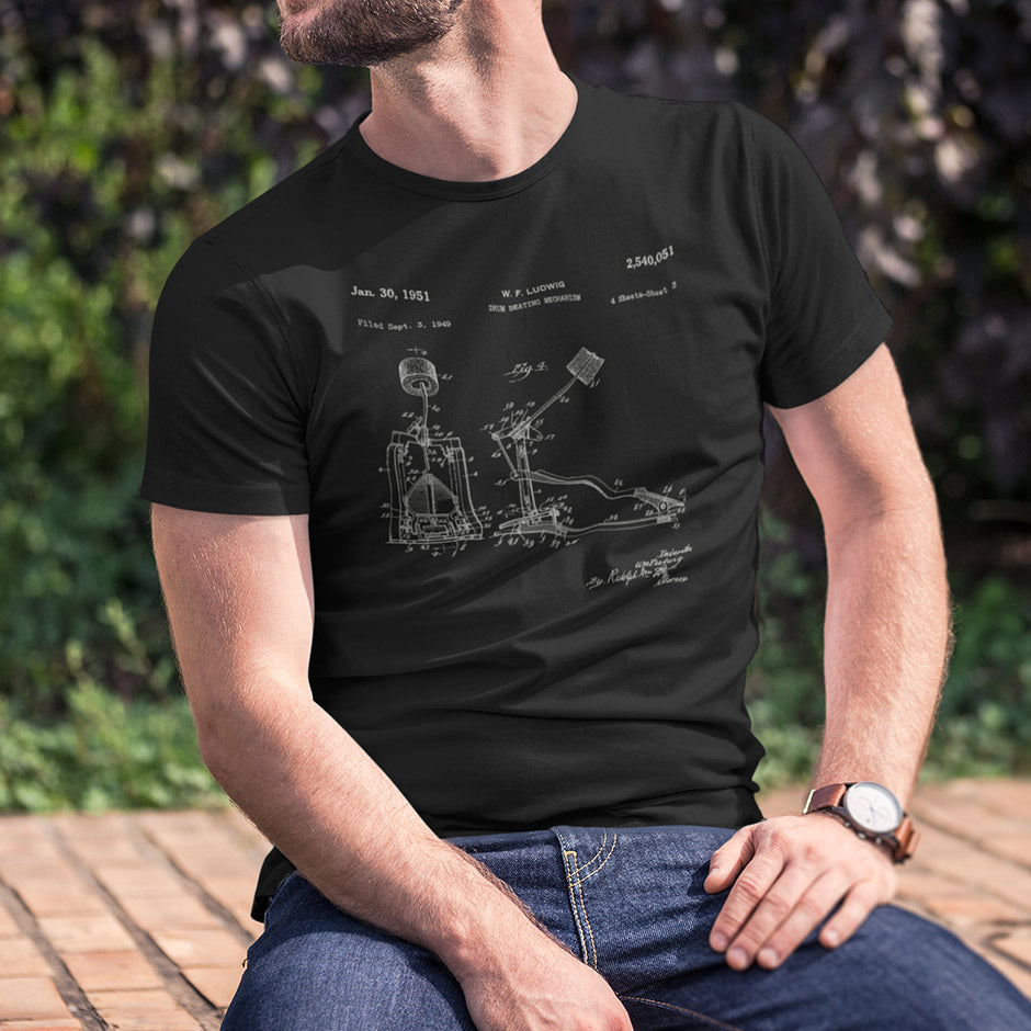 guy wearing a drummer shirt featuring a 1951 patent for a bass drum beater. Music shirt by Dodo Tees come in sizes S-3XL. 