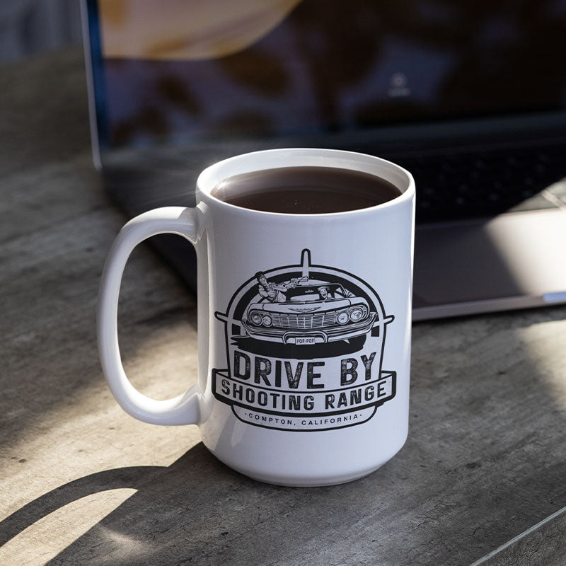 desk with laptop and funny mug with drive by shooting range logo