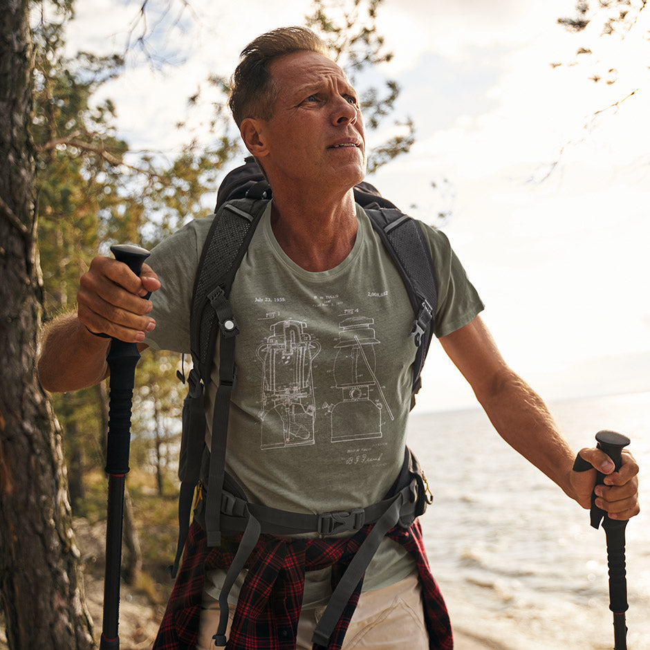 man modeling the Dodo Tees hiking shirts featuring a 1935 lantern patent. The camping shirts for men are side-seamed and made from heather fabric. 