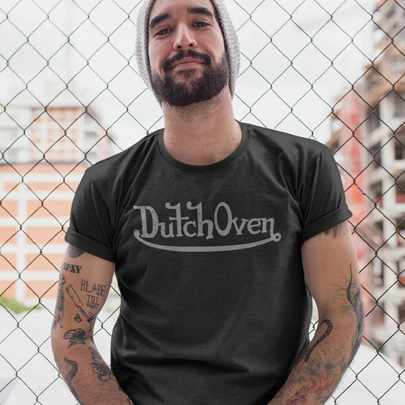 man by fence wearing hilarious t shirt for guys with dutch oven logo