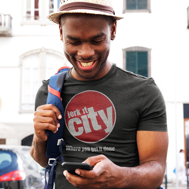 man looking at phone wearing novelty t shirt with jerk it city logo