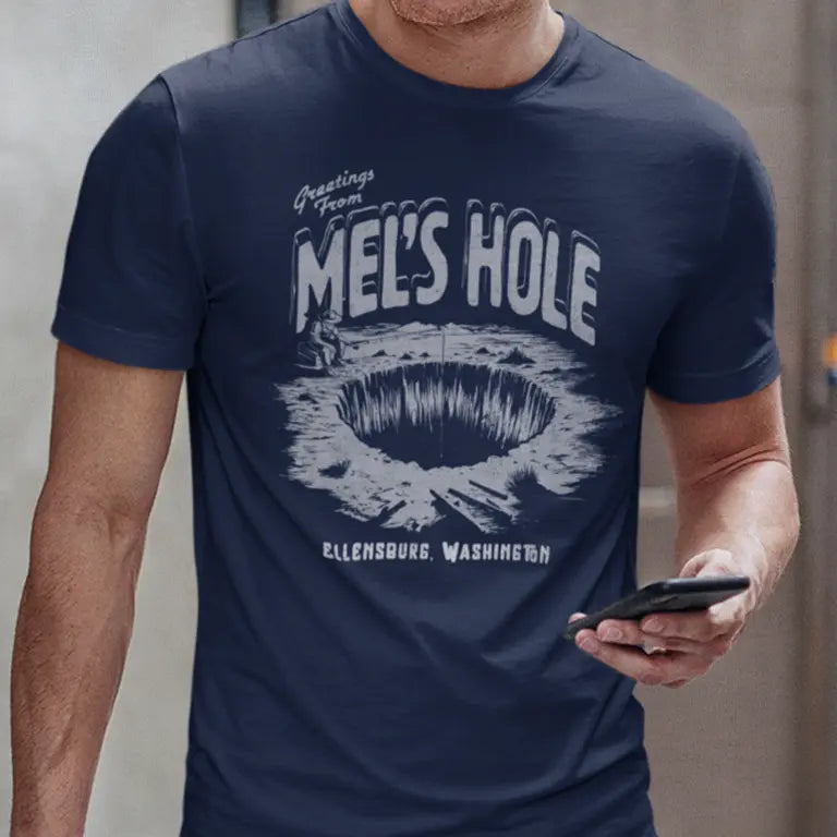 Navy Blue Mel Waters Hole t shirt worn by a man holding a phone.