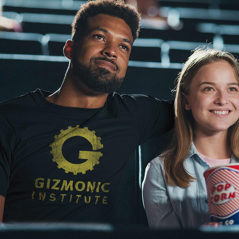 Man in theater wearing movie shirt by Dodo Tees. The Gizmonic Institute Horror Movie T Shirt is distressed