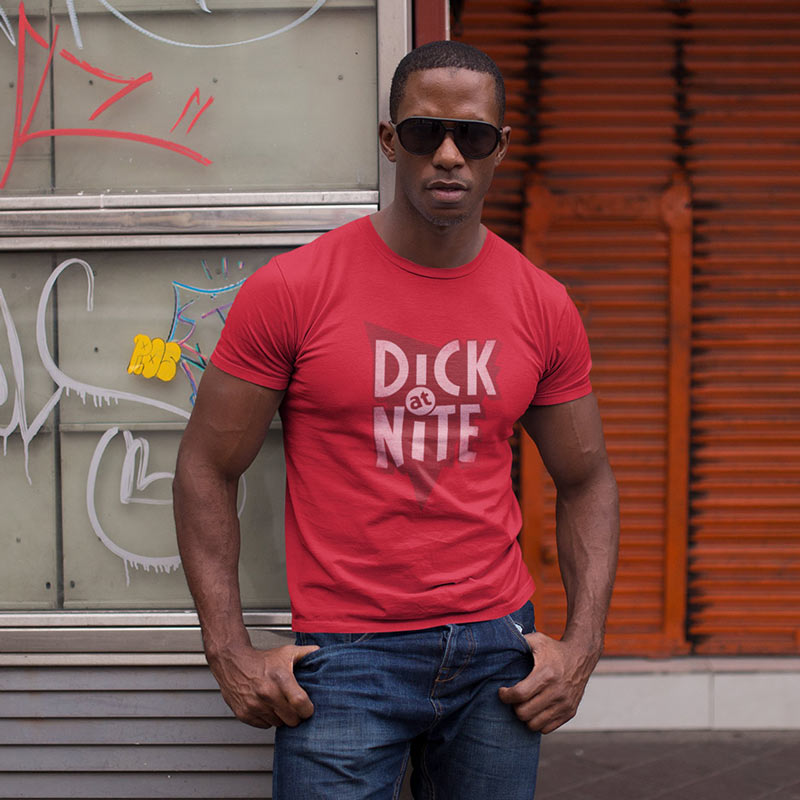 man posing in front of graffiti wearing parody shirt with dick at nite vintage style logo printed on the front of his shirt