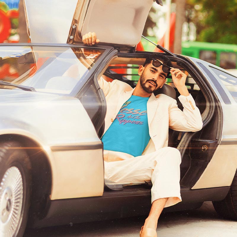 model wearing retro t shirt with gradient jesse and the rippers logo in teal and cream suit in delorean car
